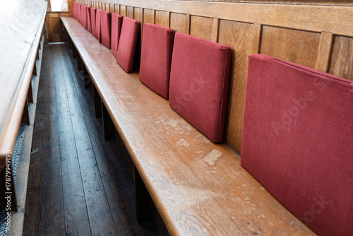 Obraz na plátně Empty, long, wooden church pew or bench with red back cushions