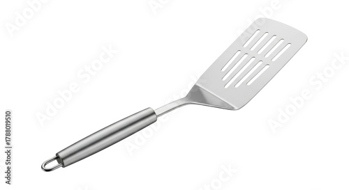 Isolated slotted turner rests at an angle, a cooking utensil with a silver handle & spatula head