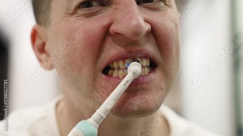 Man brushing teeth with electric toothbrush for oral hygiene