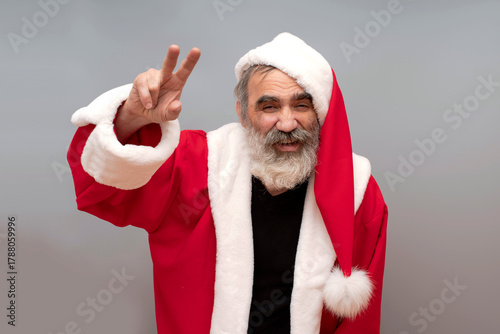 Bad Santa Claus, portrait on gray background. Natural beard, red hat, suit.