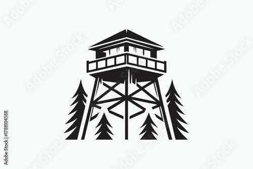 Isolated black and white fire lookout tower surrounded by evergreen trees stands silhouetted