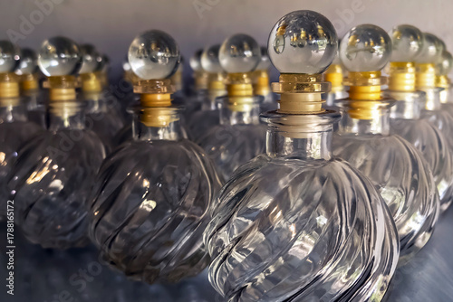 Collection of vintage clear glass jars with lids. Antique apothecary style containers displayed on old shelves.  Old vintage glass jars with lids on wooden table. Vintage Glass Container Jar Product.