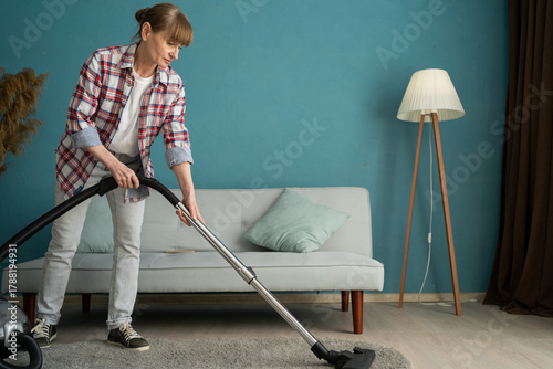 woman vacuum cleaning carpet in the living room. housekeeping