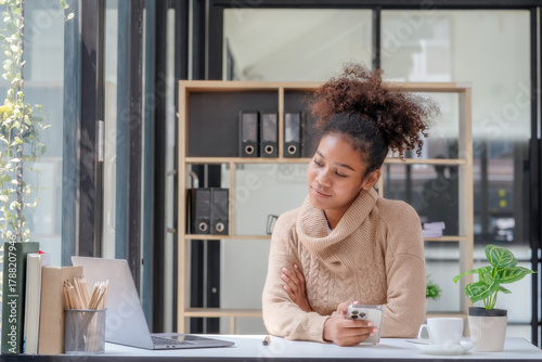A happy professional businesswoman worker employee sitting at a desk working on a laptop in a corporate setting. A smiling female student using computer technology learning online, doing web research.