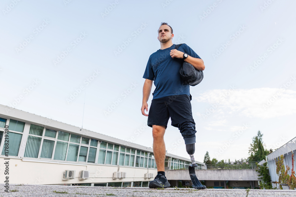 Fototapeta premium A man with disability is walking and exercising outdoors, showcasing his determination while using a prosthetic leg.
