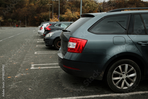 Row of parked vehicles in an outdoor parking lot on a cloudy day. The concept conveys daily routine, transport, and urban life