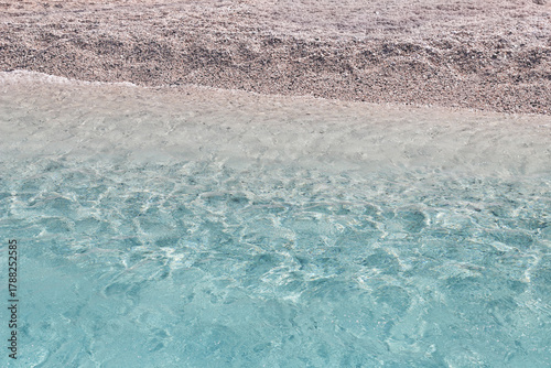 Fototapeta Naklejka Na Ścianę i Meble -  Crystal clear sea water and sandy beach texture. Minimal seascape background with turquoise transparent water and pebble sand.