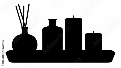 Silhouette of reed diffuser, bottle, and candles arranged on a tray in a simple black and white image