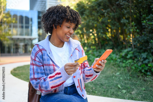 Smiling African American woman shopping online holding credit card