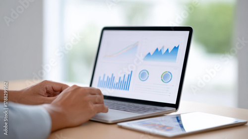Focused business person working on laptop with data analysis on screen. financial report with chart and graph showing marketing information and corporate strategy