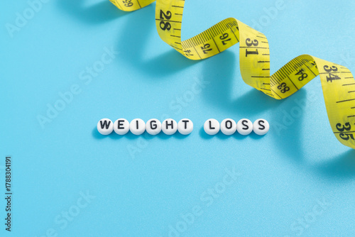 Yellow tape measure with text Weight Loss on light blue background