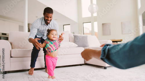 Fotografie Family At Home Encouraging Baby Daughter To Take First Steps