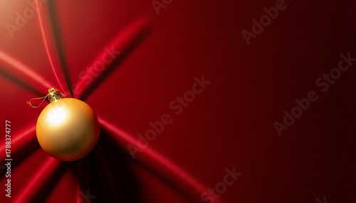 Luxurious golden Christmas bauble resting on rich, draped red velvet fabric with dramatic folds and shadows. A bold, elegant composition evoking opulence and festive grandeur.