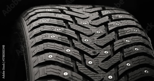 Studded winter tire rotating on black background, loop-ready