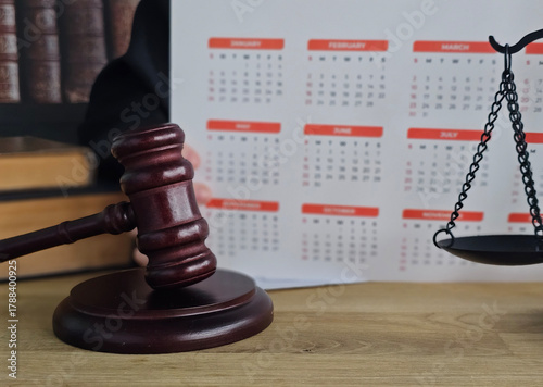 Foto Judge gavel and balance scale on a desk beside a calendar indicating an importan