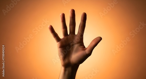 A raised hand shows five fingers against a warm orange gradient background in soft focus light.