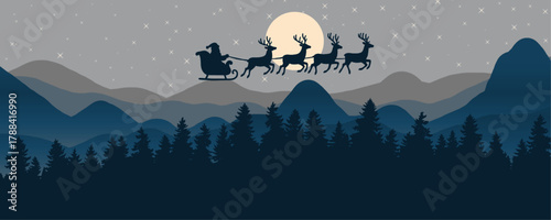 Silhouette of Santa Claus in his sleigh pulled by reindeer flying over a dark pine forest with mountains in the background under a starry night and full moon.