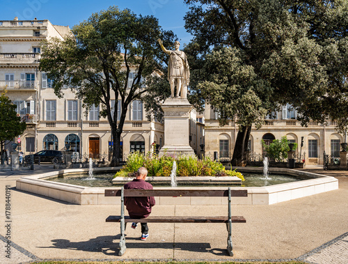 Fototapeta Naklejka Na Ścianę i Meble -  Beautiful fountain with statue of Antonin, a Roman emperor statue in Nîmes, Provence, France, Europe