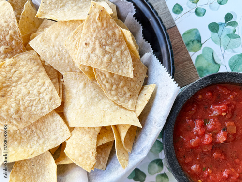 Crispy tortilla chips served with fresh salsa on a decorative table with green foliage