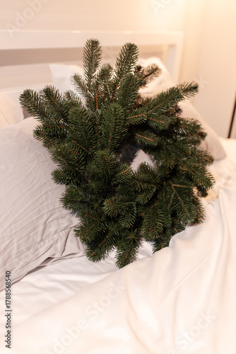 bedroom christmas decor. home interior for new years celebration. festive wreath, christmas tree. white sheets. pretty