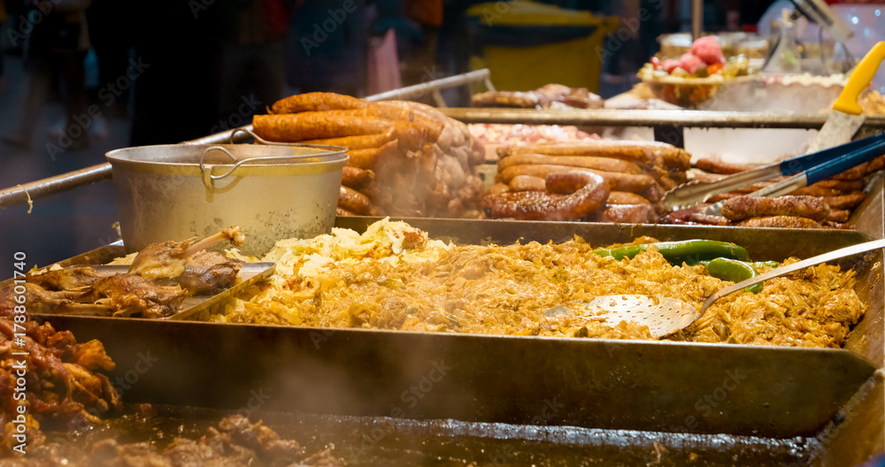 Ταπετσαρία Close up of steaming sausages, sauerkraut, and other street food cooking on a ho