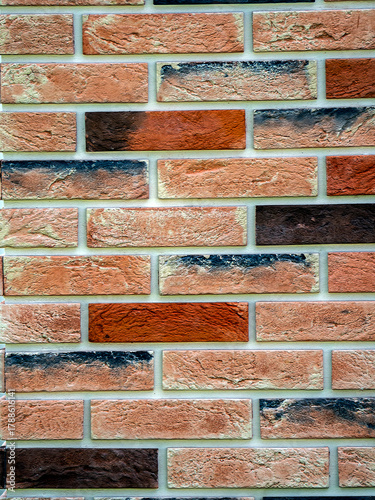 Decorative neat masonry made of multicolored bricks. Abstract geometric vertical background for your design. Copy space.