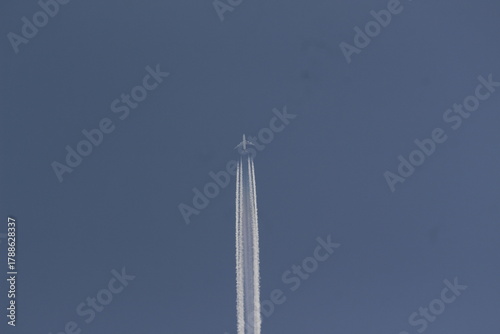 Boeing 747 jumbo jet passing by in high speed leaving contrails behind.