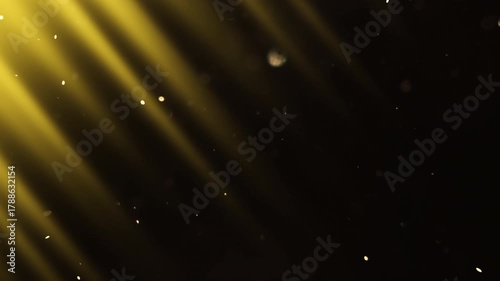 Diagonal beams of yellow light shimmer in the darkness and slowly  flying fairy dust. 4K slow motion video at 60 fps.