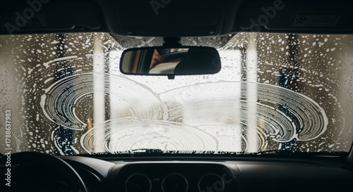 View through a car windshield covered in soap at a car wash
