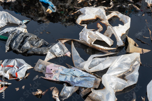 Fotografía Plastic waste pollutes water surface during daylight in a neglected area near a