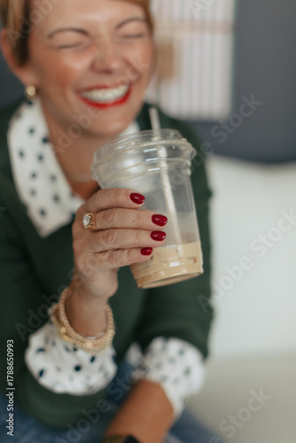 Midlife woman laughing enjoying iced coffee