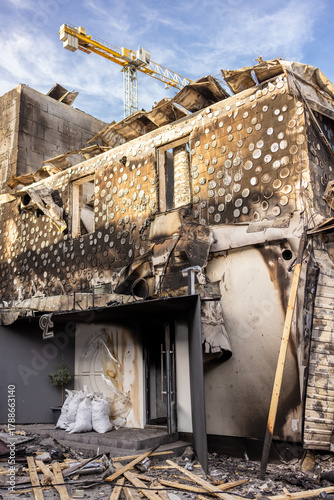 War. The aftermath of Russian airstrikes on a peaceful Ukrainian city. A hospital and a recreation center were destroyed. Charred wall with circular burn marks and debris from fire damaged building.