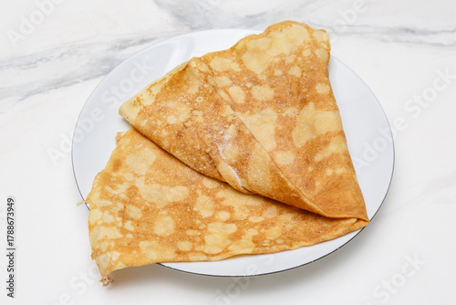 Schilderij op canvas Crêpe au sucre sur une assiette blanche, posée sur une table en marbre