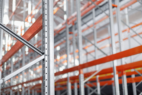 Background industrial metal shelving racks in a warehouse or factory. The steel structure with orange beams and metal efficient storage system. Logistics industrial design concepts