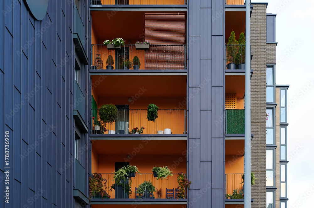 Obraz premium modern apartment balconies with colorful facades featuring plants and outdoor furniture. urban living, vertical gardens, and contemporary architecture highlighted in vibrant city scene.