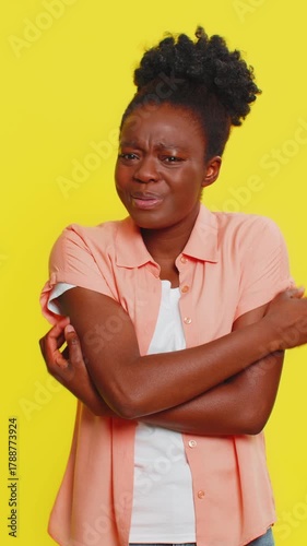 African American woman scratches hand arm and neck, showing irritation frustration from allergy symptoms. Black girl on yellow background demonstrates discomfort, common signs of an allergic reaction