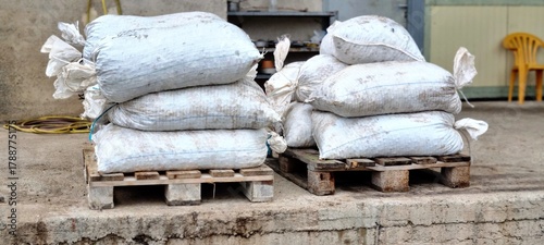 Stacks of sacks filled with freshly harvested olives on wooden pallets outside an olive mill