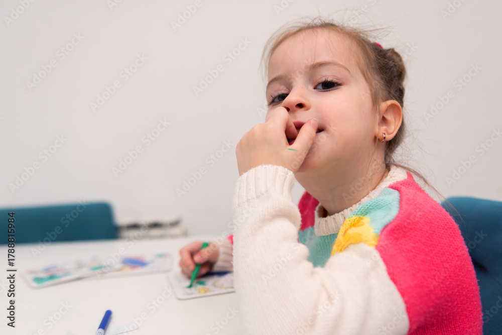 Naklejka premium Funny and Expressive Little Girl Drawing and Playing with Markers – Learning Through Emotions