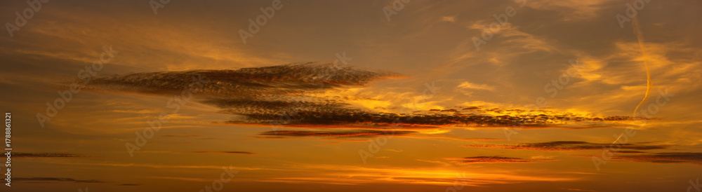 Fototapeta premium Sunset sky. Photo of an orange-red cloudscape. Evening glow. Beautiful wide cloud background. Widescreen panorama. Panoramic photography