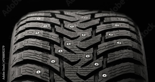 Studded winter tire rotating on black background, loop-ready