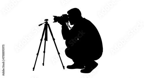 Silhouette of a photographer crouching and taking a picture with a camera on a tripod