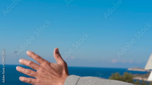 Passenger enjoys a scenic coastal drive, extending their hand out the car window to feel the refreshing air against their skin, embracing the freedom and joy of the open road
