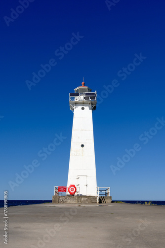Low angle image of the concrete and stone pier leading to the Sodus Point Lighthouse on Lake Ontario in New York State on a beautiful afternoon