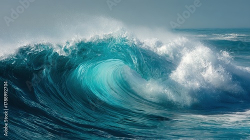 Turquoise waves roll and crash onto the beach under a clear sky. The sunlight highlights the waters movement creating a beautiful display of natures power.