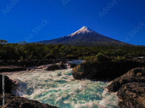 Snow-capped volcano with turquoise water and forest in summer