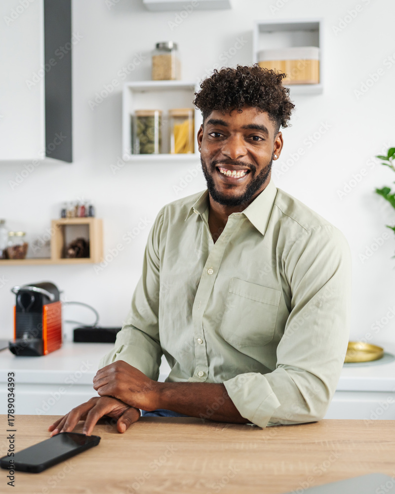 Fototapeta premium Young black man smiling while leaning on kitchen counter