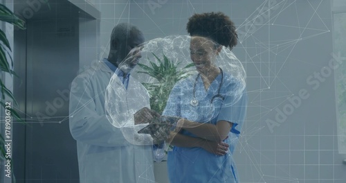 Reviewing doctor using tablet in hall nurse wearing blue scrubs lab coat stethoscope brain hologram