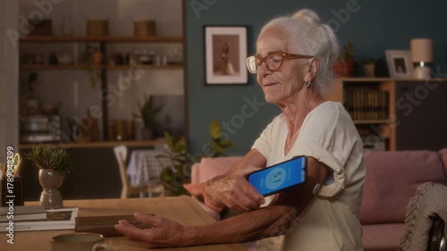 Medium shot of elderly gray-haired Caucasian woman in short sleeved top checking glucose with smartphone app, placing to monitor patch on upper arm, nodding with satisfaction at good result