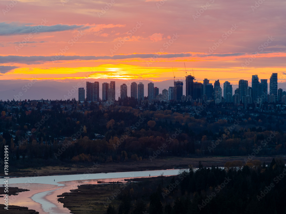 Fototapeta premium Sunset Over Burnaby Skyline: Vibrant Horizon, Cityscape, and River Below at Dusk