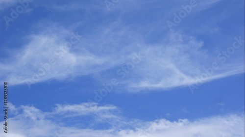 Puffy clouds travel gracefully across a wide bright sky reflecting simplicity and harmony in a tranquil landscape. Relaxation.